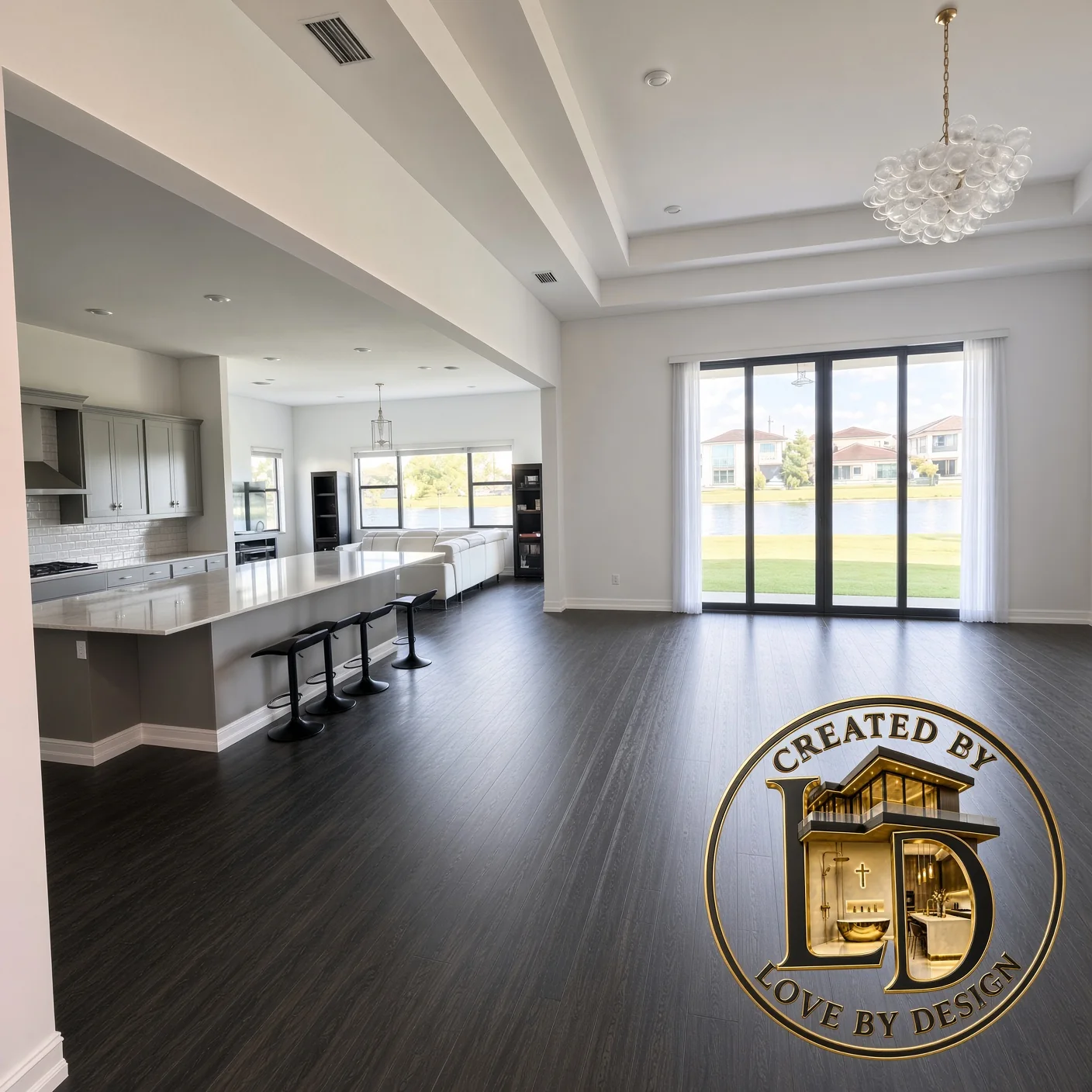 Great room with dark plank floors, a long kitchen island, a chandelier and lake-view doors