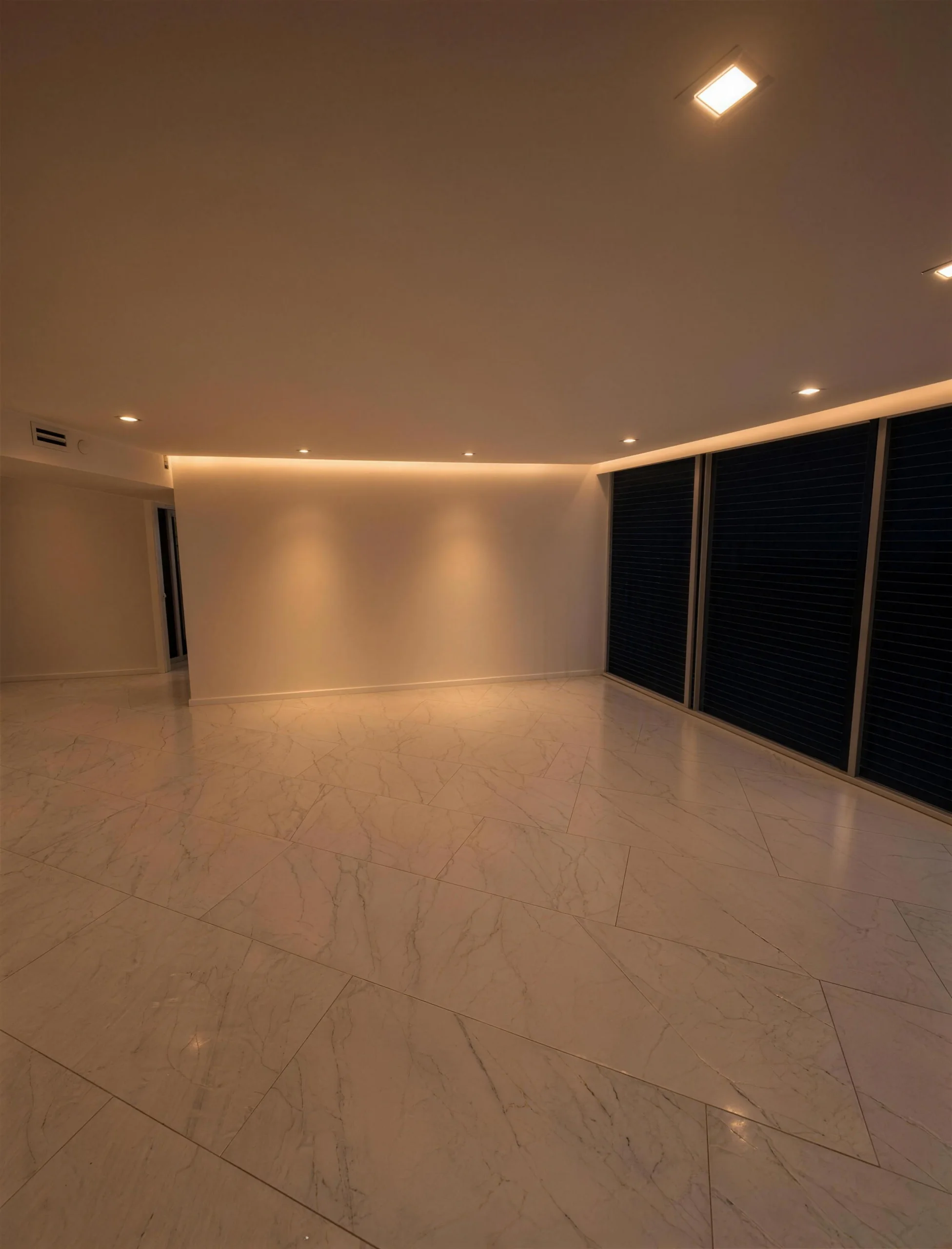 Open living room with warm cove lighting and large marble-look floor tile