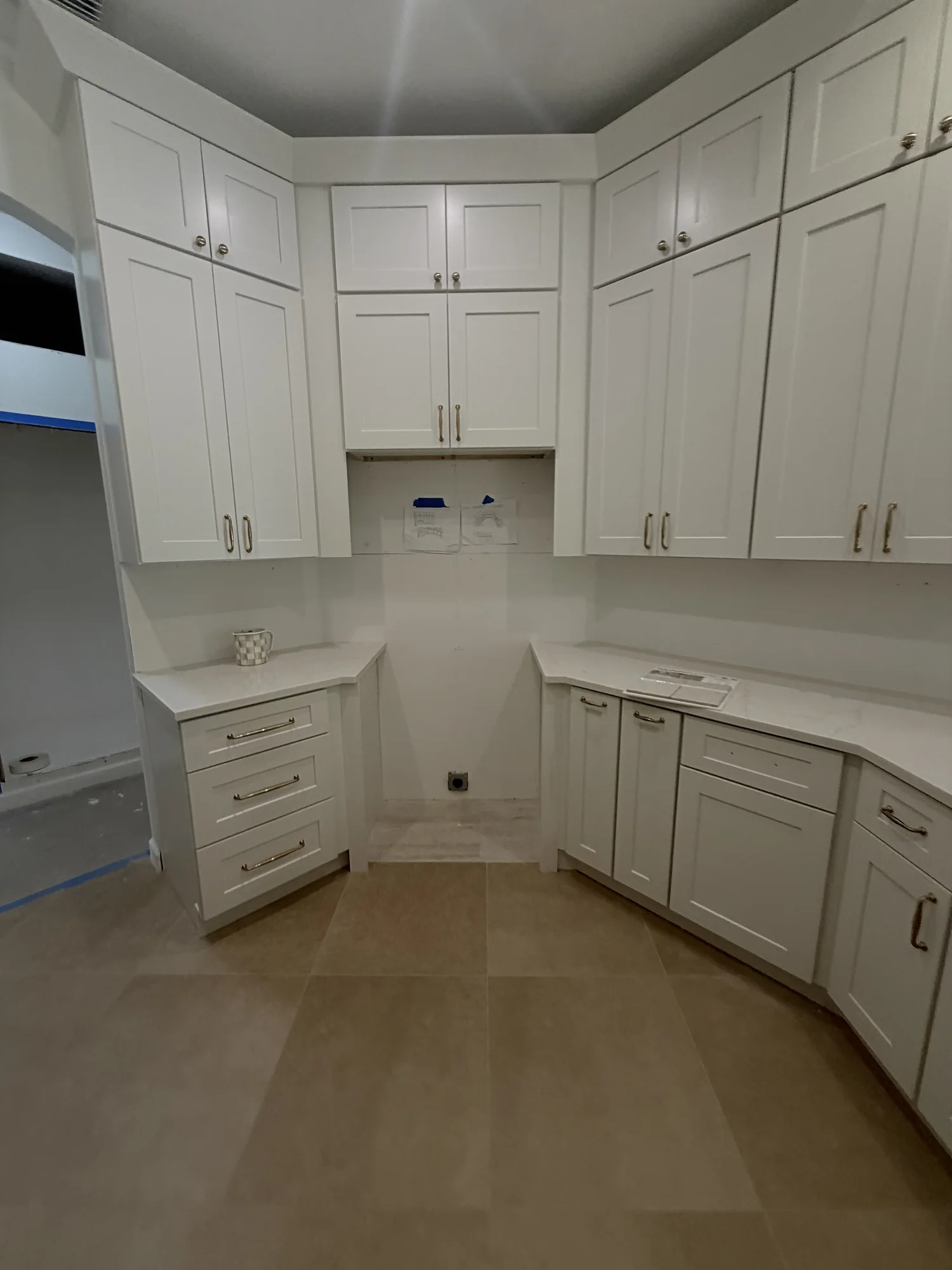 White Shaker cabinets and pale stone countertops before appliance installation