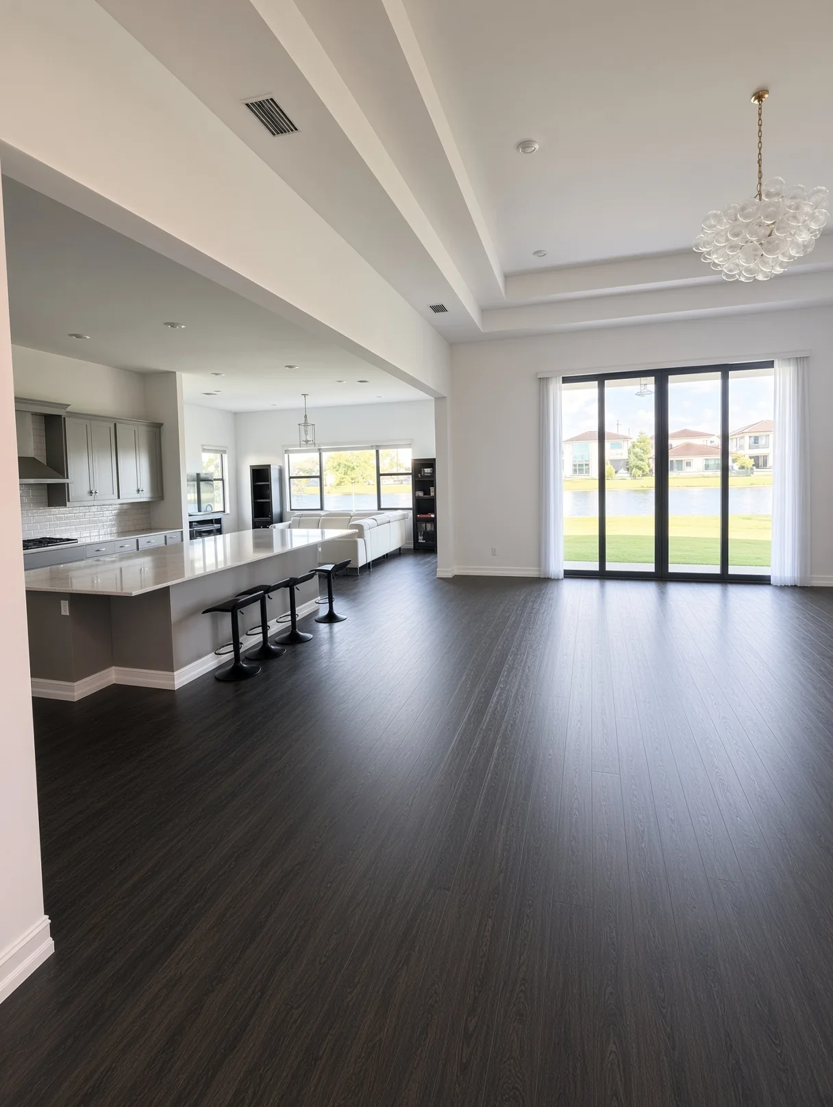 Open great room with dark plank floors, a kitchen island and lake-view doors