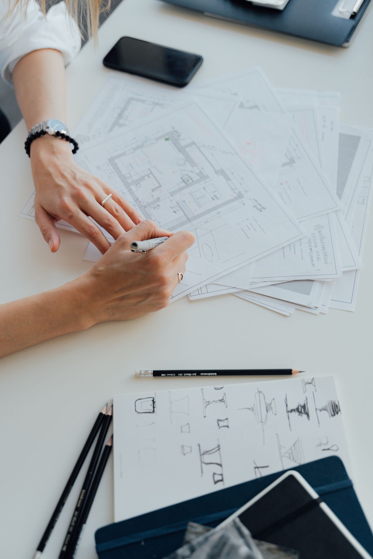 Hands marking up architectural plans at a desk