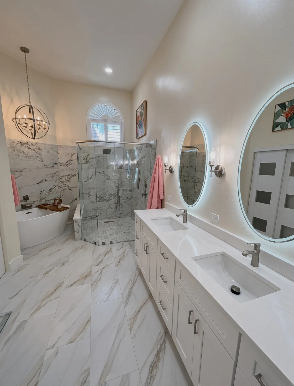 Double vanity with lit round mirrors, a glass shower and marble-look floor tile