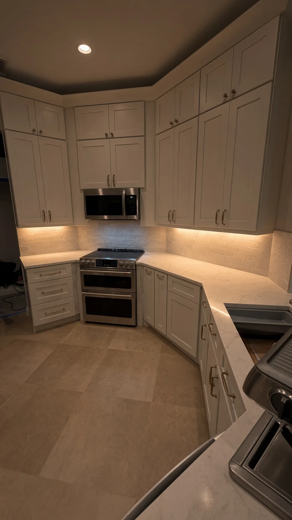 White shaker kitchen at night with under-cabinet lighting and a double-oven range