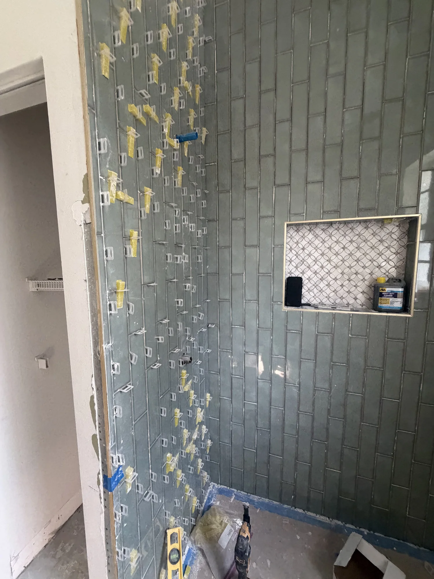 Green shower wall tile and a recessed niche during installation