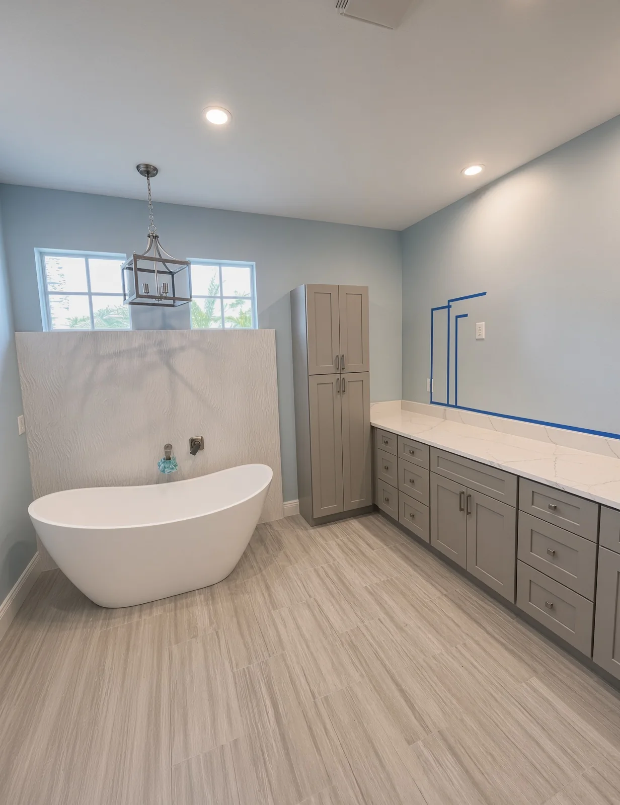 Bathroom with a freestanding tub, pendant light and long grey vanity during final touches
